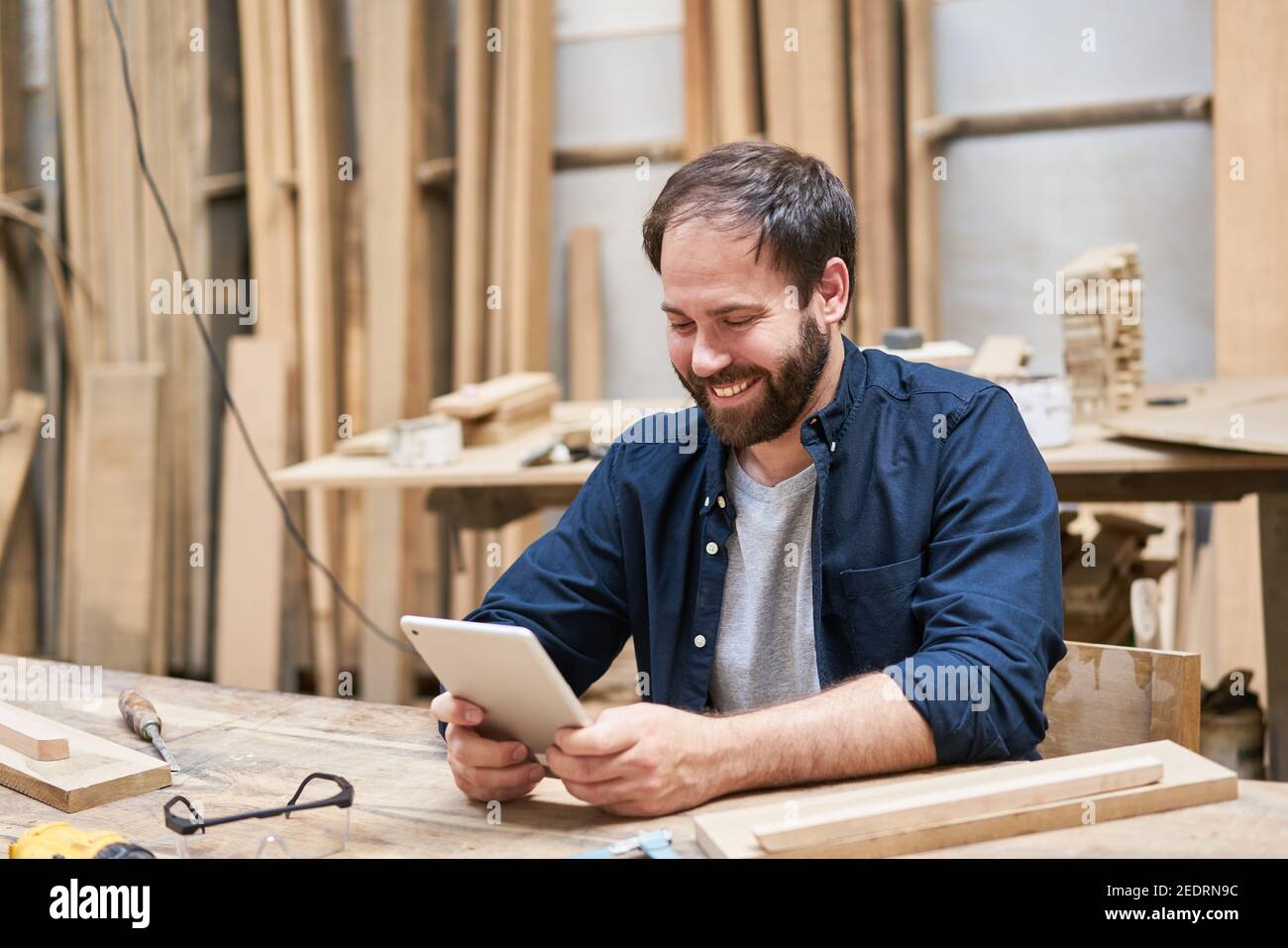 Artigiano con il computer tablet durante la chat video online nel officina di falegnameria Foto Stock