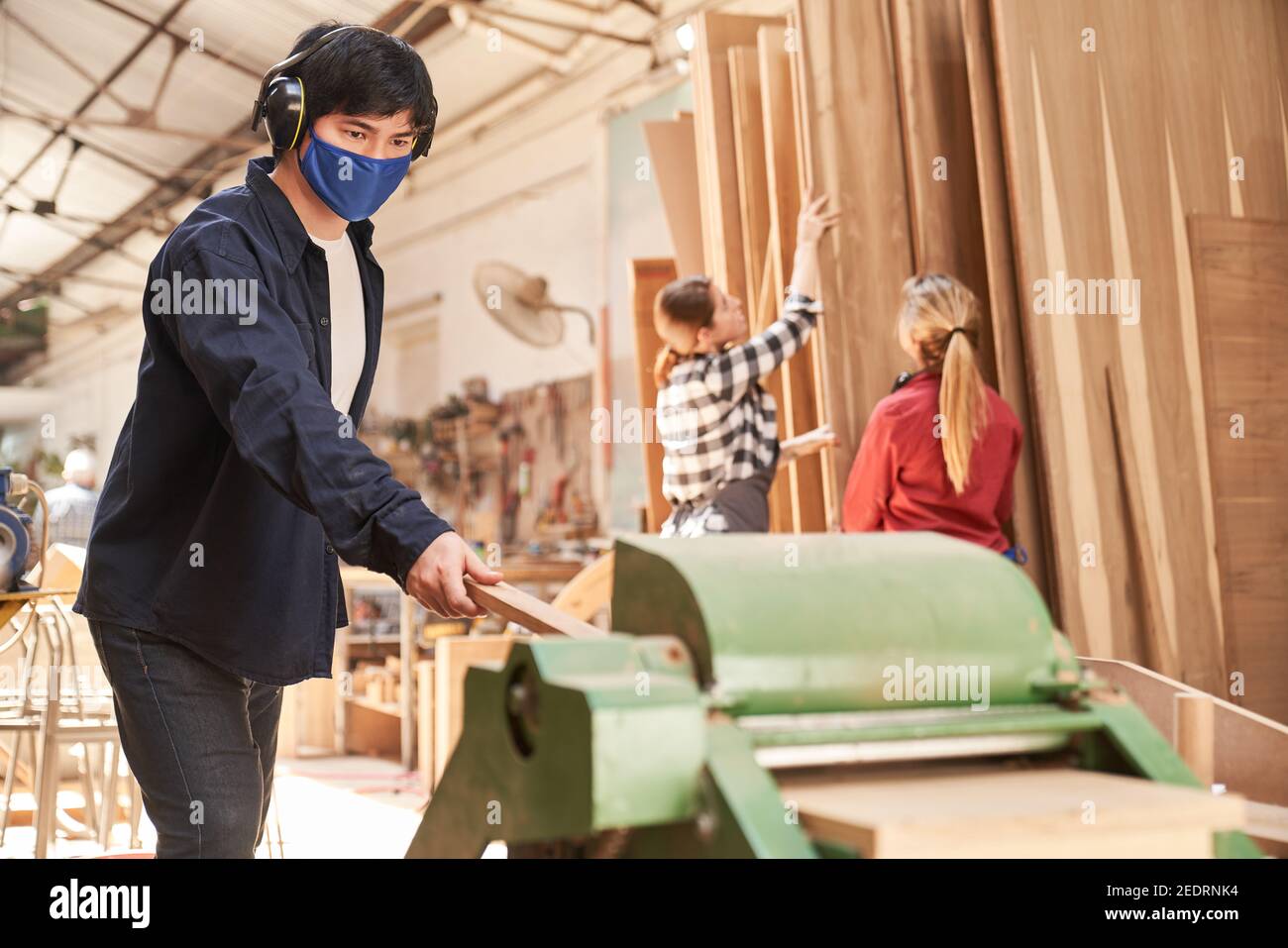Giovane uomo che lavora come un artigiano con maschera facciale perché Di Covid-19 sulla piantatrice Foto Stock