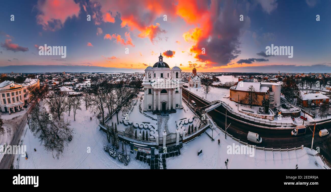 Vista panoramica aerea della cattedrale e della chiesa nella piccola città europea coperta di neve al luminoso tramonto d'inverno splendidi tramonti e nuvole. Drone. Wint Foto Stock