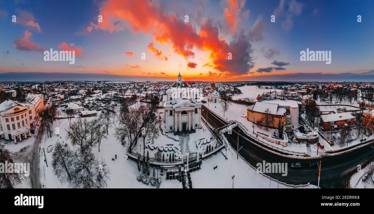 Vista panoramica aerea della cattedrale e della chiesa nella piccola città europea coperta di neve al luminoso tramonto d'inverno splendidi tramonti e nuvole. Drone. Wint Foto Stock