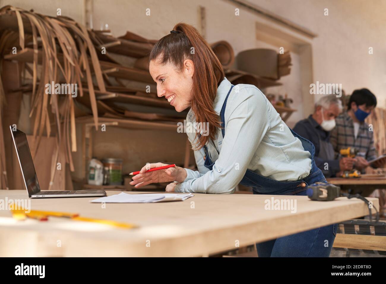 Donna artigiana che consiglia i clienti in video chat in officina di carpenteria Foto Stock