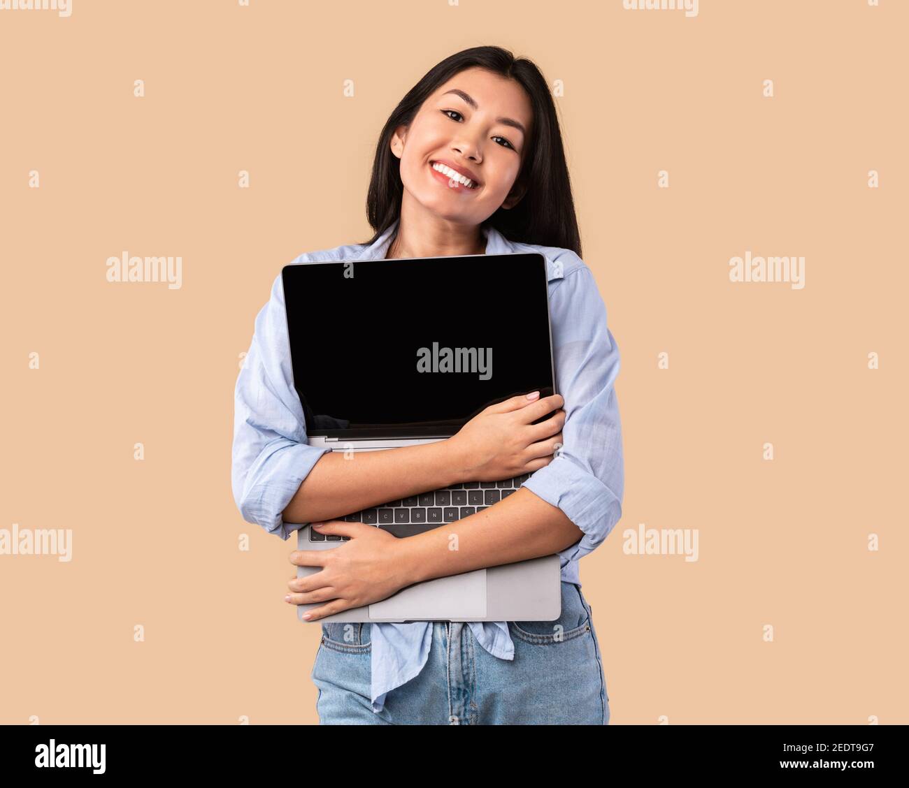 Entusiasta donna asiatica che agguanava personal computer in studio Foto Stock