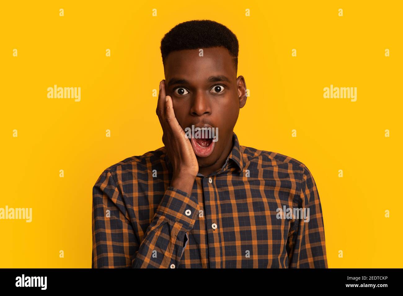 Incredibile. Portraif di Young Black Man scioccato toccare faccia con eccitazione Foto Stock