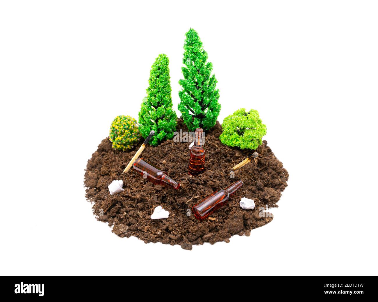 Composizione di foresta giocattolo in miniatura con bottiglie di birra, rifiuti di carta e partite che giacciono intorno.il concetto di mantenere foreste e parchi puliti. Foto Stock