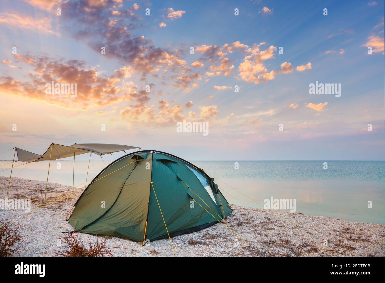 Campeggio tenda su una spiaggia tranquilla vicino all'acqua contro il tramonto cielo sfondo, felice estate campo Foto Stock