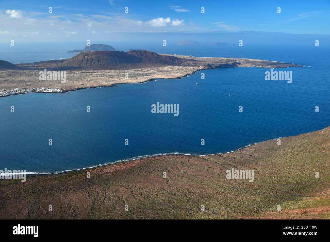 La Graciosa, una piccola isola vulcanica nel nord di Lanzarote, Spagna. Oceano blu e un cielo blu con alcune nuvole bianche. Lontano sullo sfondo l'Isl Foto Stock