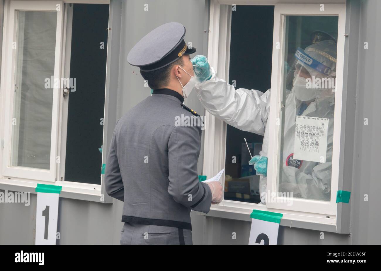 Seoul, Corea del Sud. 14 Feb 2021. Un'infermiera che indossa una tuta protettiva personale (PPE) preleva un campione di tampone da un cadetto dell'Accademia militare di Corea durante un test COVID-19 gratuito in una clinica di improvvisazione. Credit: SOPA Images Limited/Alamy Live News Foto Stock