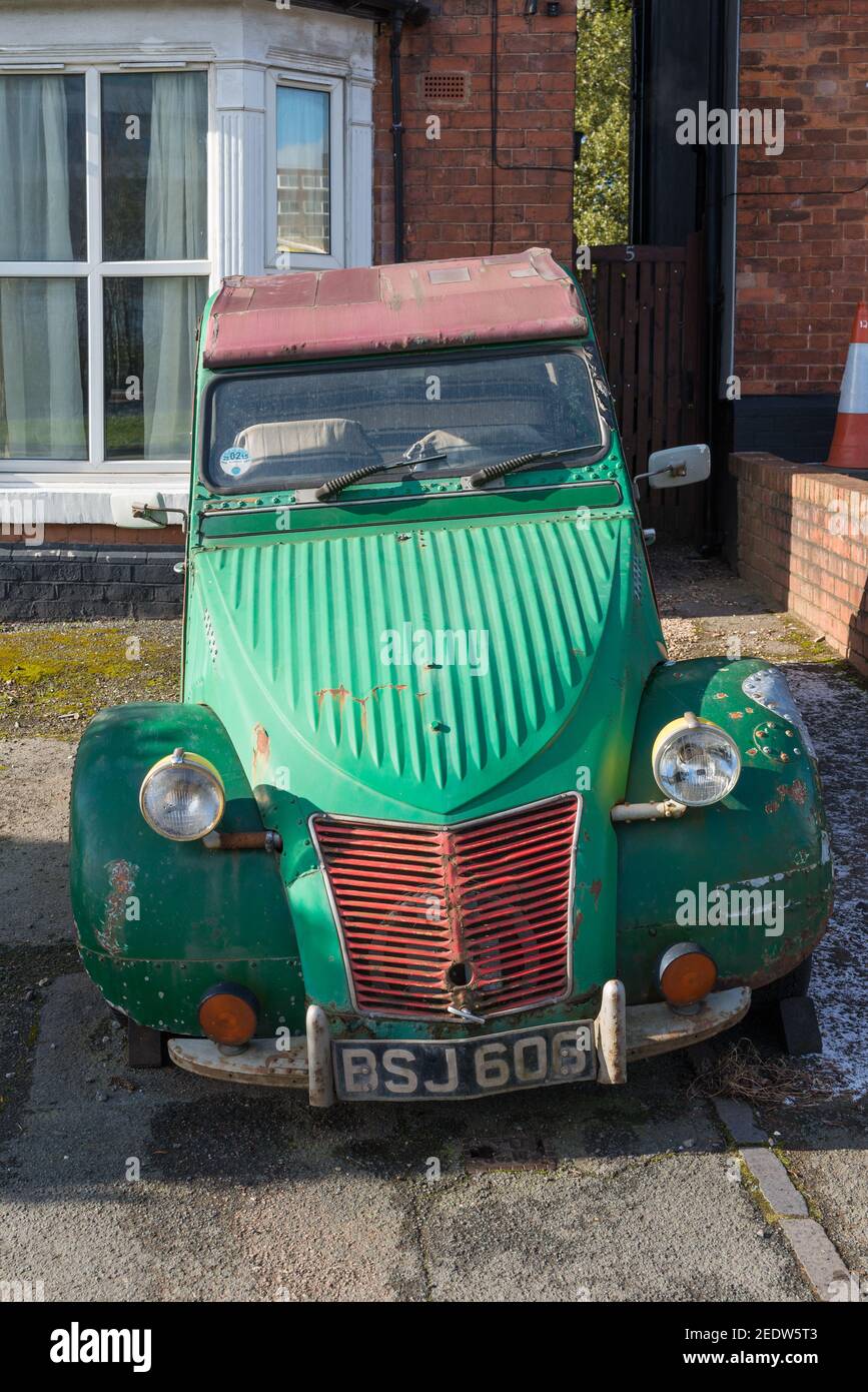 La vecchia Citroen 2CV verde e arrugginita è parcheggiata su una strada anteriore fuori di una casa Foto Stock