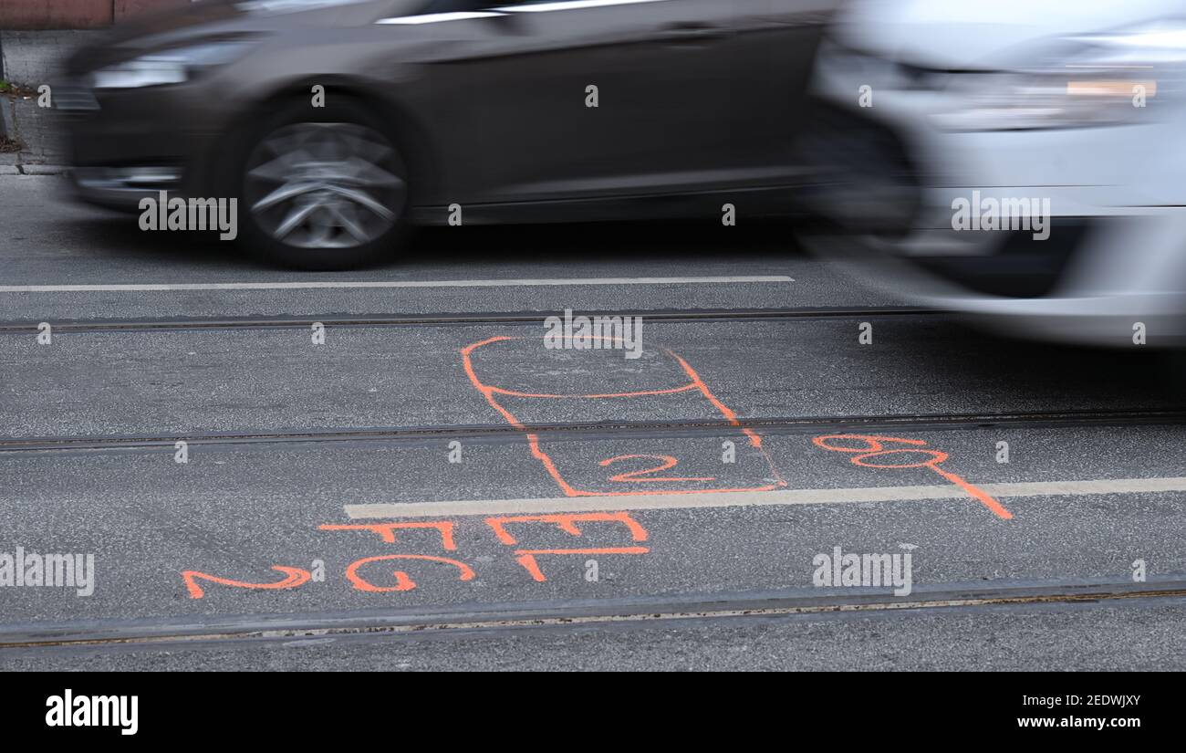 15 febbraio 2021, Hessen, Francoforte sul meno: Le auto passano davanti a un pennarello dove una vittima di un incidente stradale mortale sabato scorso si trovava nel quartiere Sachsenhausen di Francoforte (scatto a velocità più lunga). Secondo le indagini della polizia finora, due pedoni sono stati colpiti da una macchina perché il conducente stava viaggiando a una velocità significativamente eccessiva. Foto: Arne Dedert/dpa Foto Stock