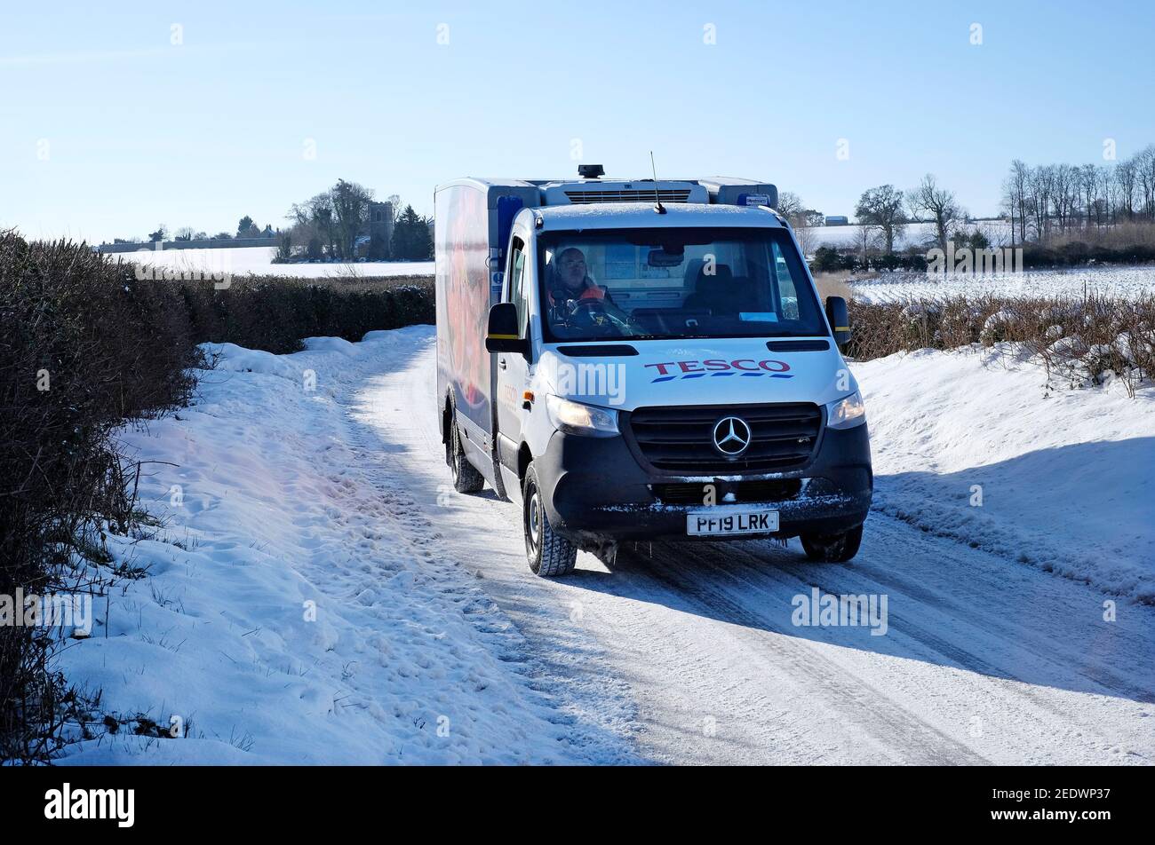 tesco home delivery furgone sulla corsia di campagna coperta di neve, norfolk settentrionale, inghilterra Foto Stock