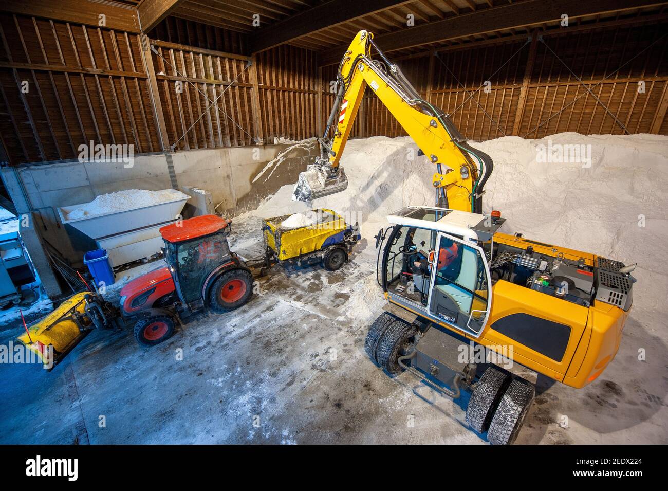 Un escavatore al lavoro in un deposito di sale utilizzato per l'anti-slittamento su una strada. Foto Stock