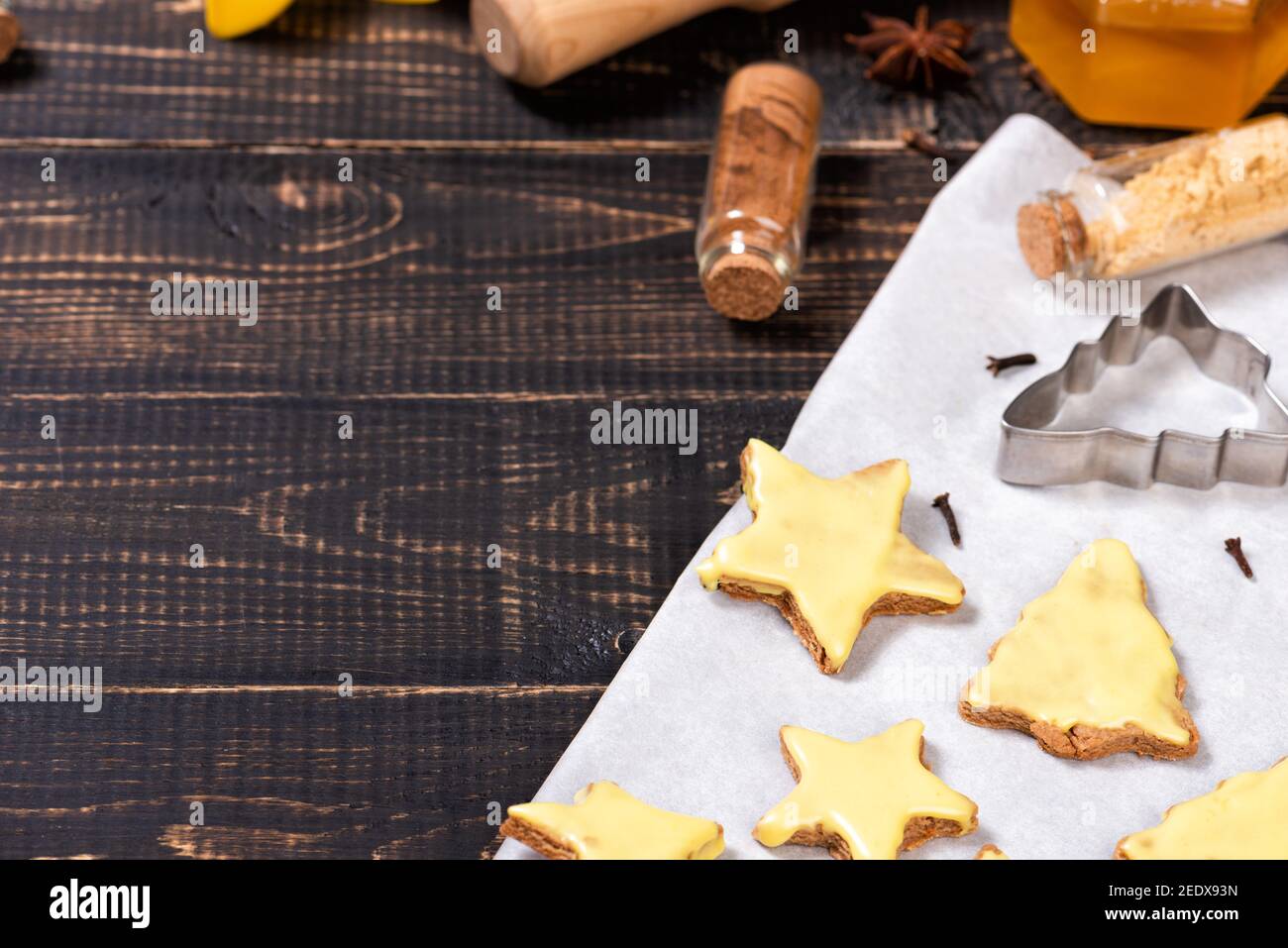 Biscotti fatti in casa al burro con glassa gialla di limone su una carta da forno e rastrelliera metallica. Cannella, arance essiccate che cucinano roba Foto Stock