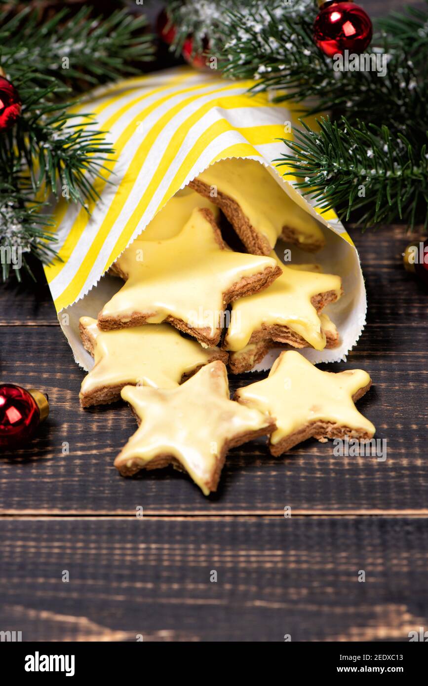 Biscotti fatti in casa al burro con glassa gialla di limone su una carta da forno e rastrelliera metallica. Cannella, arance essiccate che cucinano roba Foto Stock