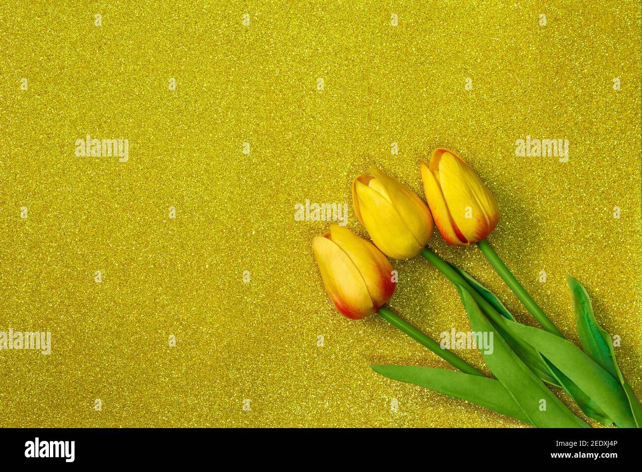 Tulipani gialli su sfondo oro glitter. Card festiva per l'8 marzo, Felice Festa della Madre, Pasqua. Spazio di copia Foto Stock