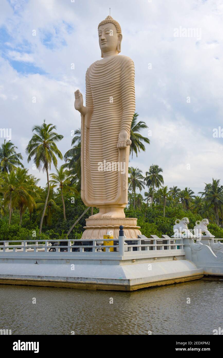 HIKKADUWA, SRI LANKA - 14 FEBBRAIO 2020: Una scultura gigante di un Buddha in piedi pari in altezza all'onda di tsunami che distrusse la costa di S. Foto Stock