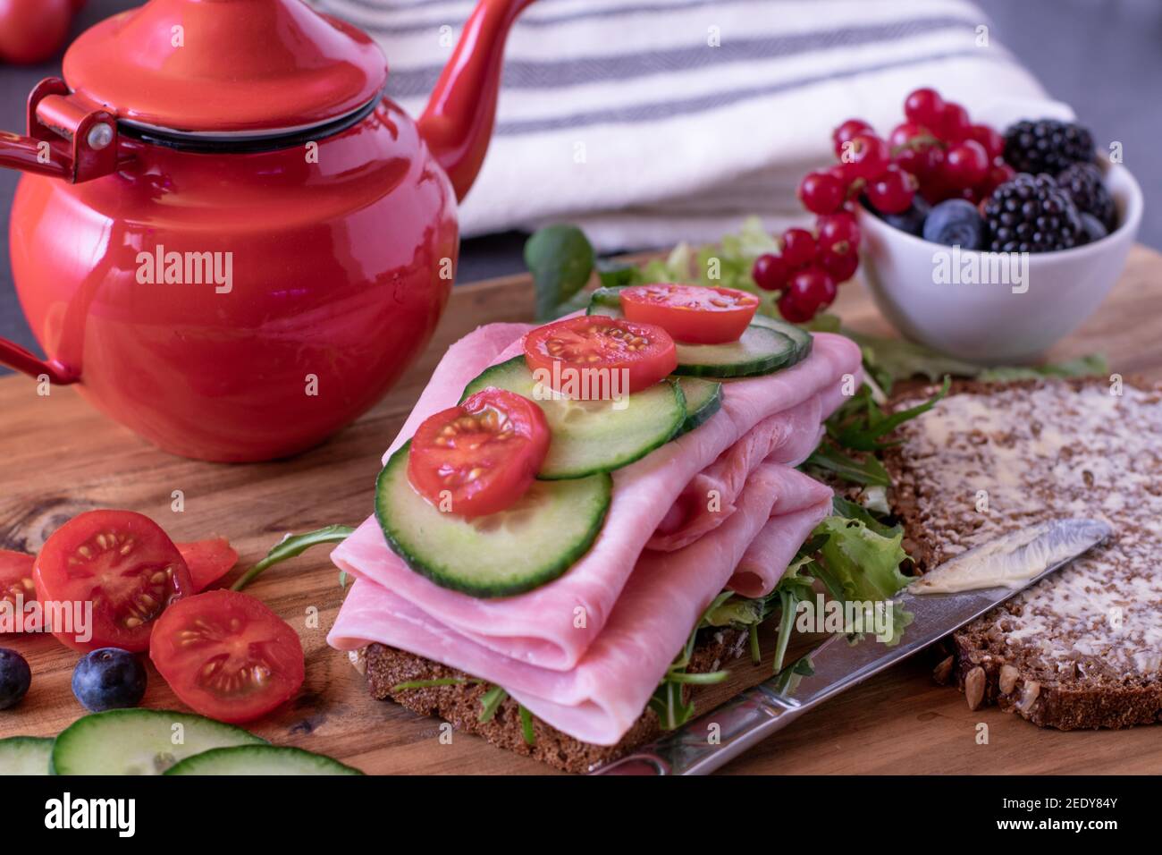 un sano sandwich per la colazione con frutta e verdura su un legno tagliere con teiera Foto Stock