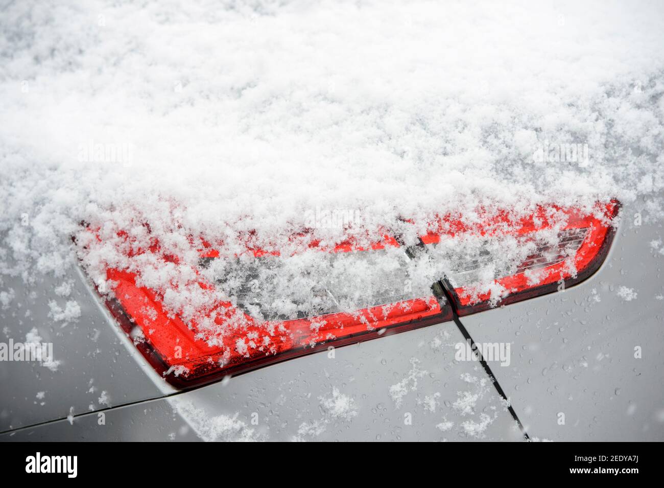 Primo piano di neve sul gruppo luci posteriori di un'auto. Foto Stock