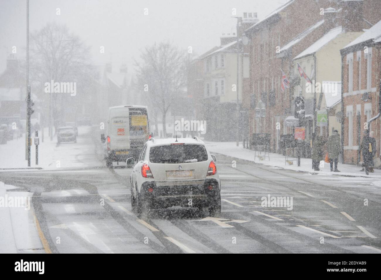 Veicoli che guidano in condizioni di neve in Market Harborough, Leicestershire, East Midlands, Inghilterra. Foto Stock