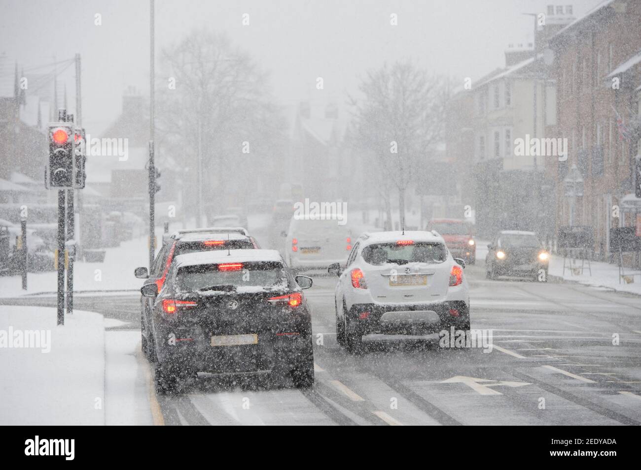 Veicoli che guidano in condizioni di neve in Market Harborough, Leicestershire, East Midlands, Inghilterra. Foto Stock