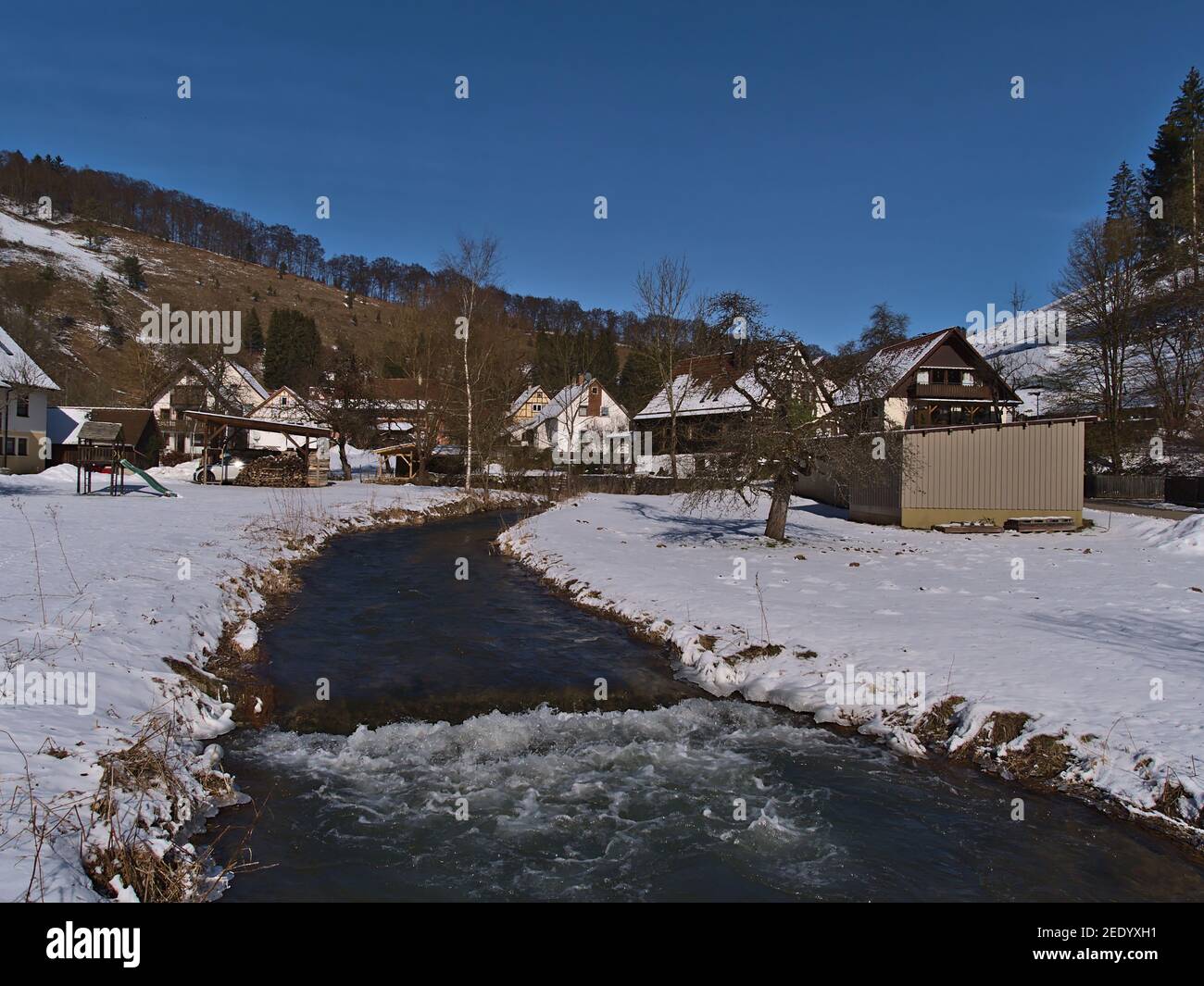 Idilliaco paesaggio invernale del piccolo villaggio rurale Gundelfingen, parte di Münsingen, Germania in Alb Svevo con il fiume Große Lauter, prato innevato. Foto Stock
