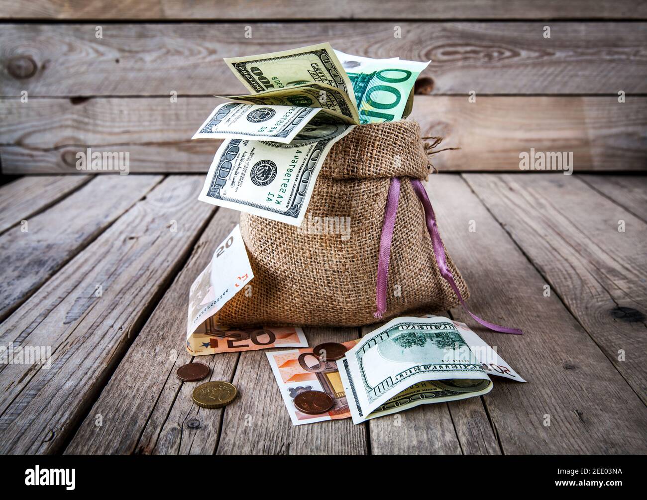 soldi in sacco di burlap su sfondo di legno e. Foto Stock