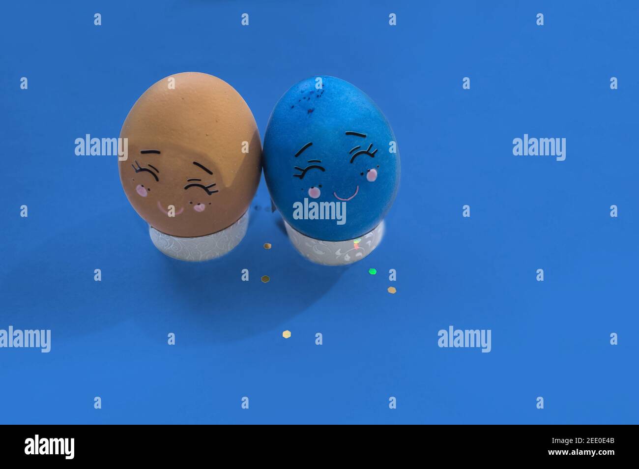uovo di pasqua marrone e blu con i volti dei cartoni animati in piedi sfondo blu Foto Stock