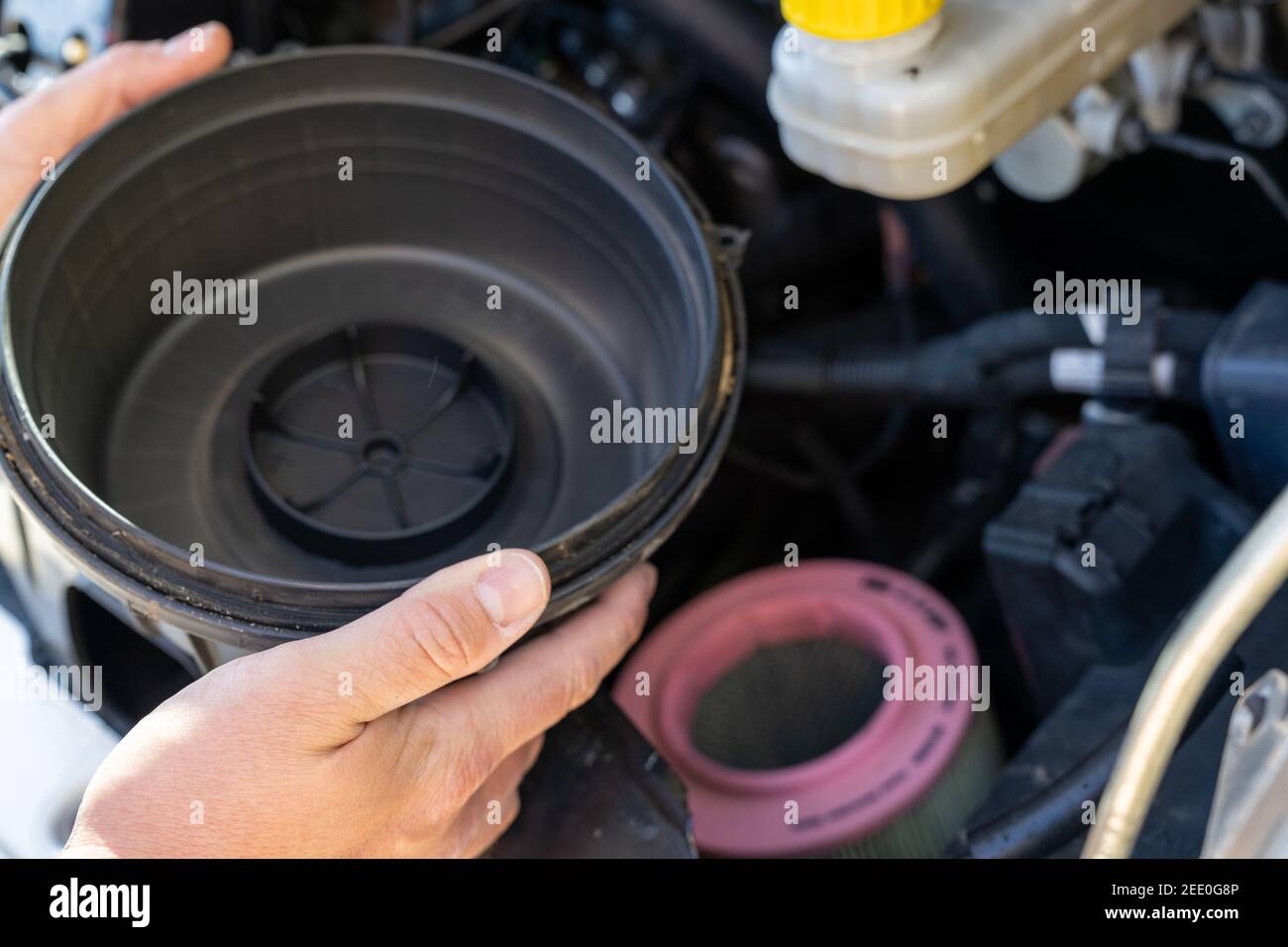 Un primo piano di mani di un controllo maschio caucasico il coperchio del filtro dell'aria di un motore Foto Stock