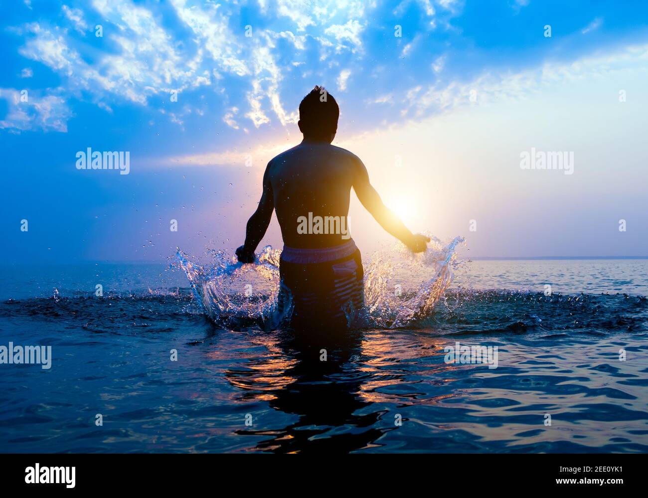 Happy Man Silhouette con spruzzi in acqua sul Tramonto sfondo Foto Stock