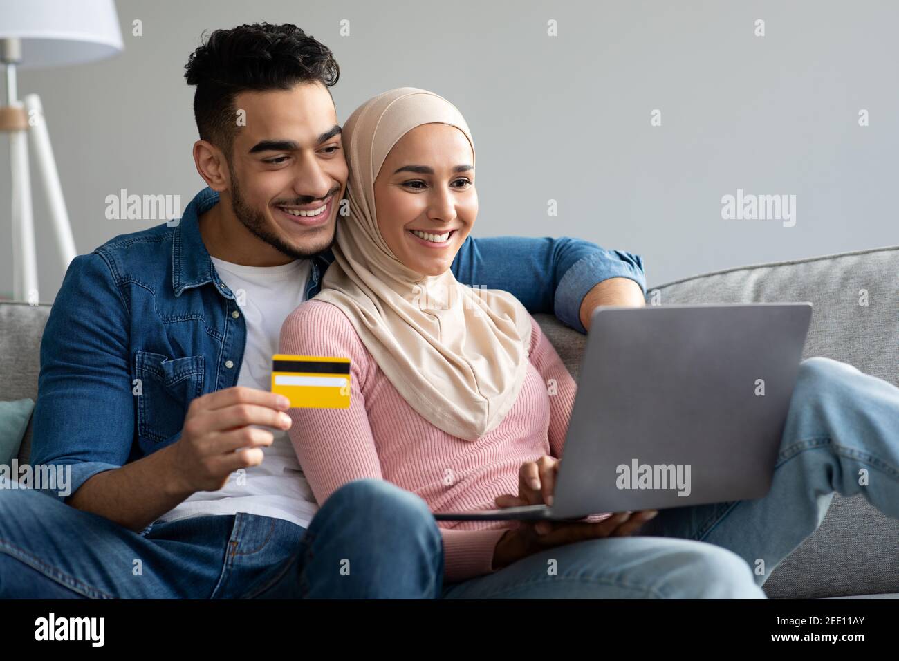 Sorridente coppia musulmana con laptop e carta di credito Foto Stock