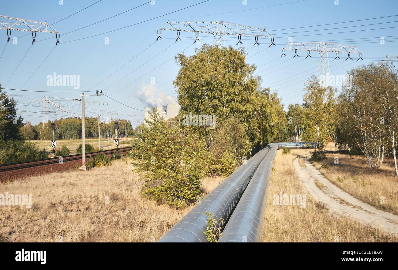 Conduttura con torri di trasmissione ad alta tensione in background in una foresta. Foto Stock
