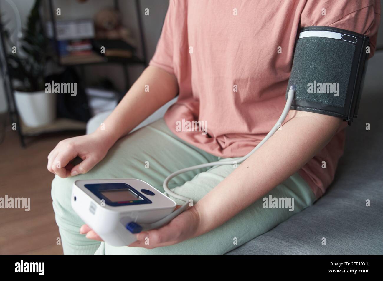 una giovane ragazza misura la sua pressione sanguigna con un tonometro Foto Stock