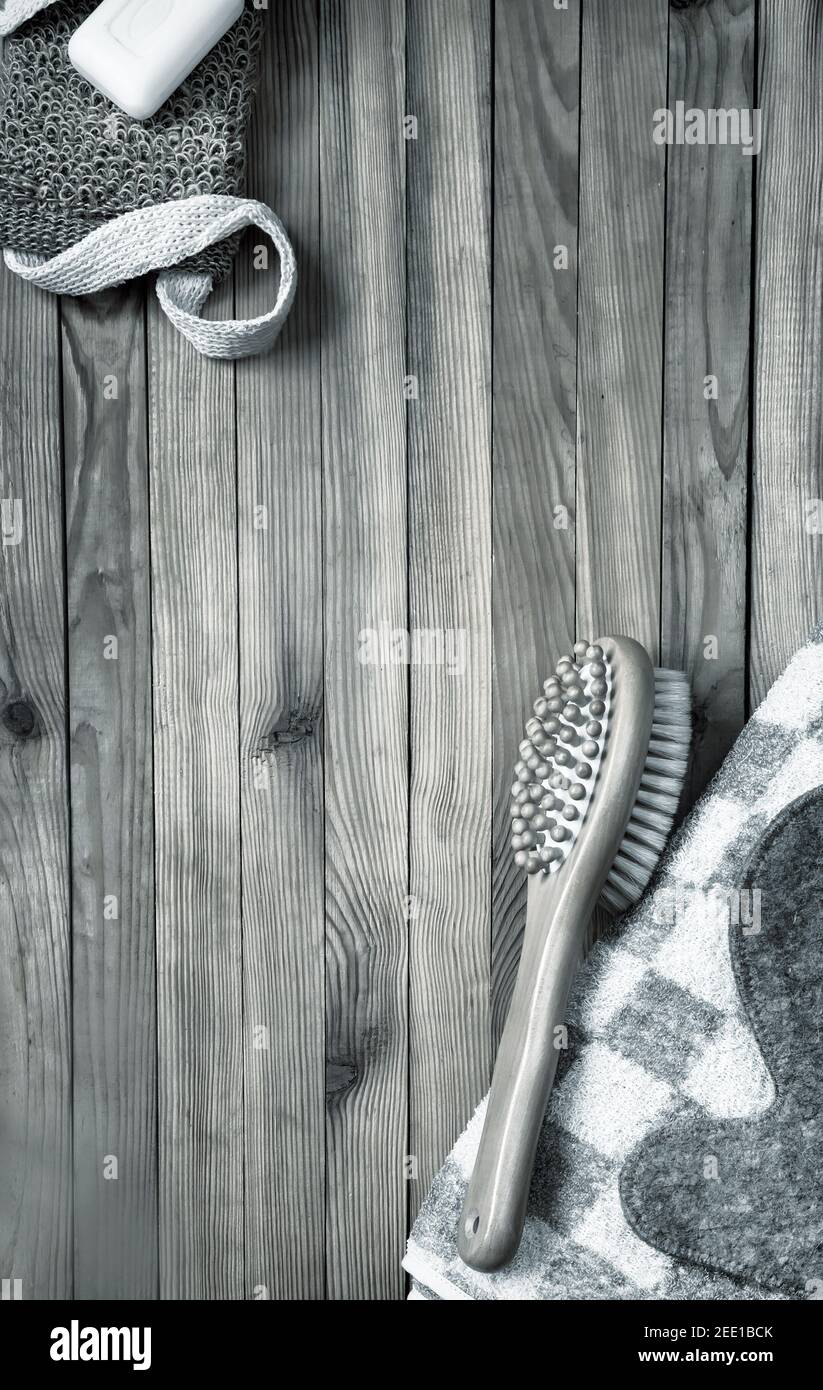 Accessori per la visita di un bagno o sauna su fondo di legno: Asciugamano, panno, spazzola per massaggi, sapone, guanto. Vista dall'alto con spazio per la copia. Disposizione piatta Foto Stock