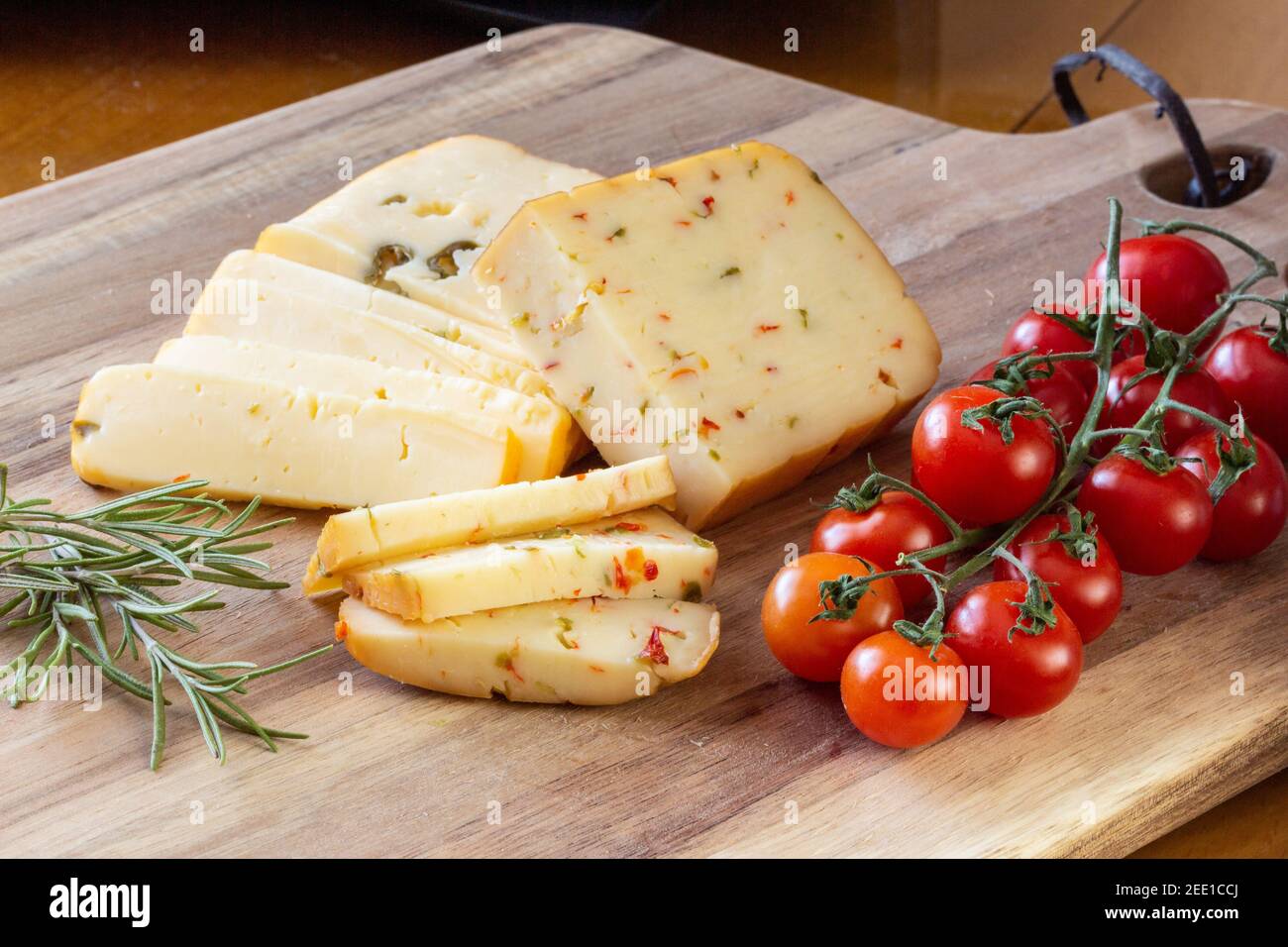 Formaggio morbido con olive e formaggio con peperoni con pomodori e rosmarino - sfondo di legno Foto Stock