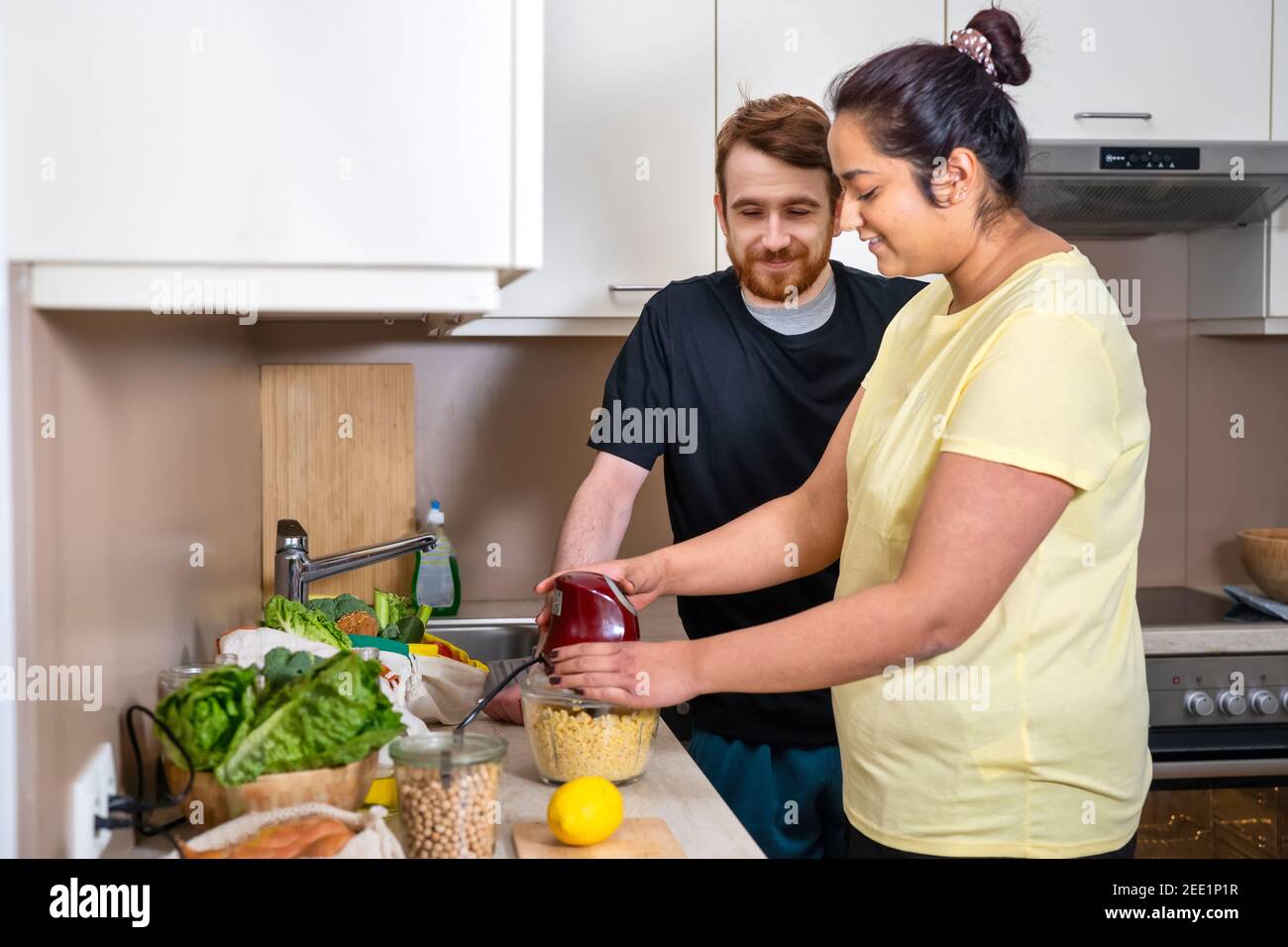 Giovane coppia di razza mista che prepara hummus vegano Foto Stock