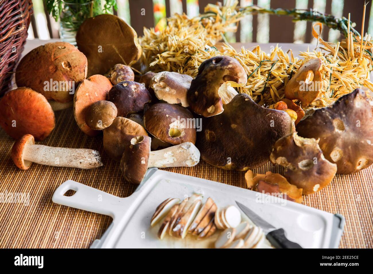 Grande mucchio di funghi freschi della foresta, funghi affettati a bordo, corona di mais su tavola di legno, preparazione per la cottura su tavola da cucina esterna. Foto Stock