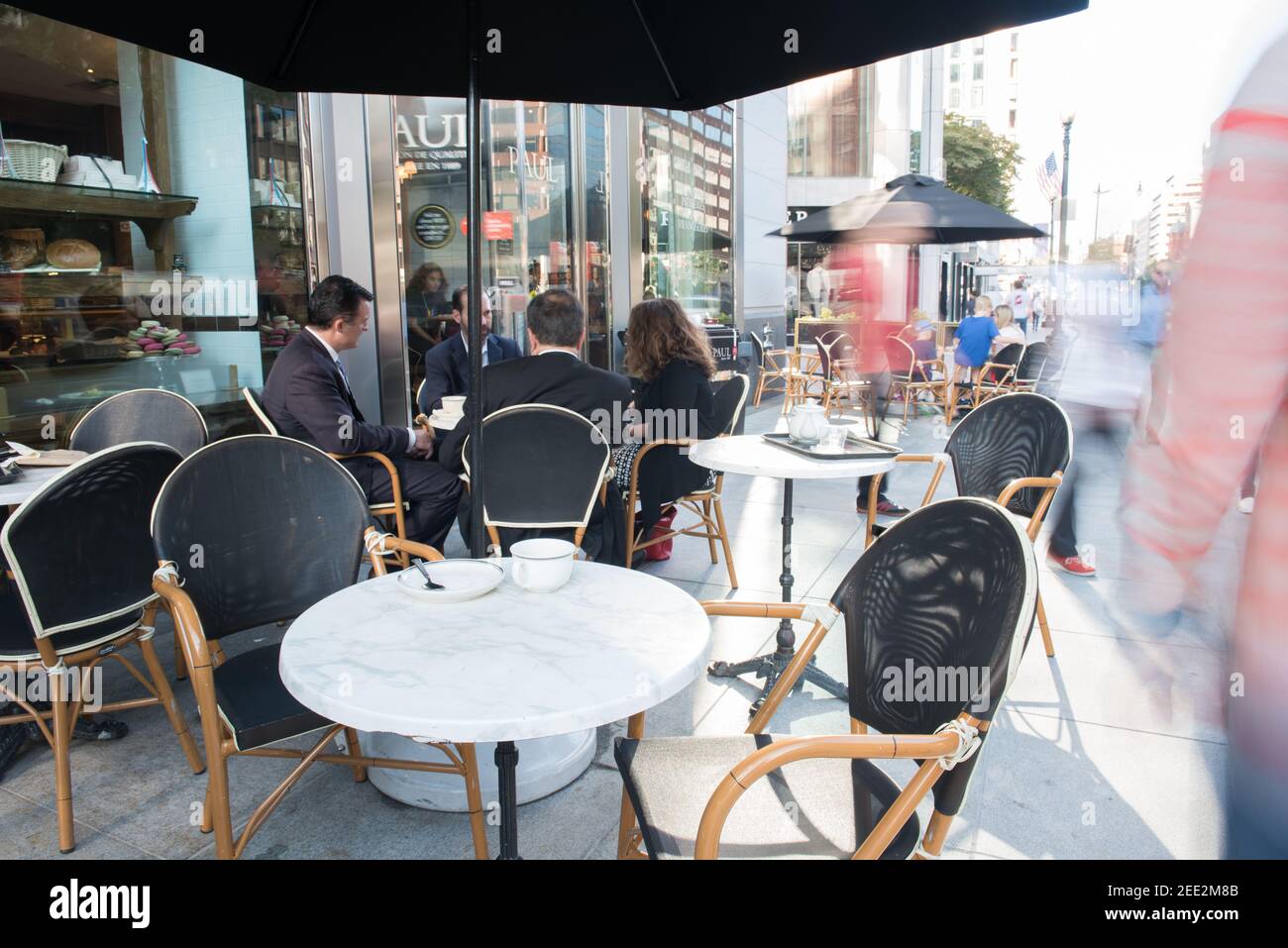 Un caffè francese con tavoli allestiti sul marciapiede è occupato durante l'ora di punta di mattina a Washington, DC. Sfocatura del movimento. Foto Stock