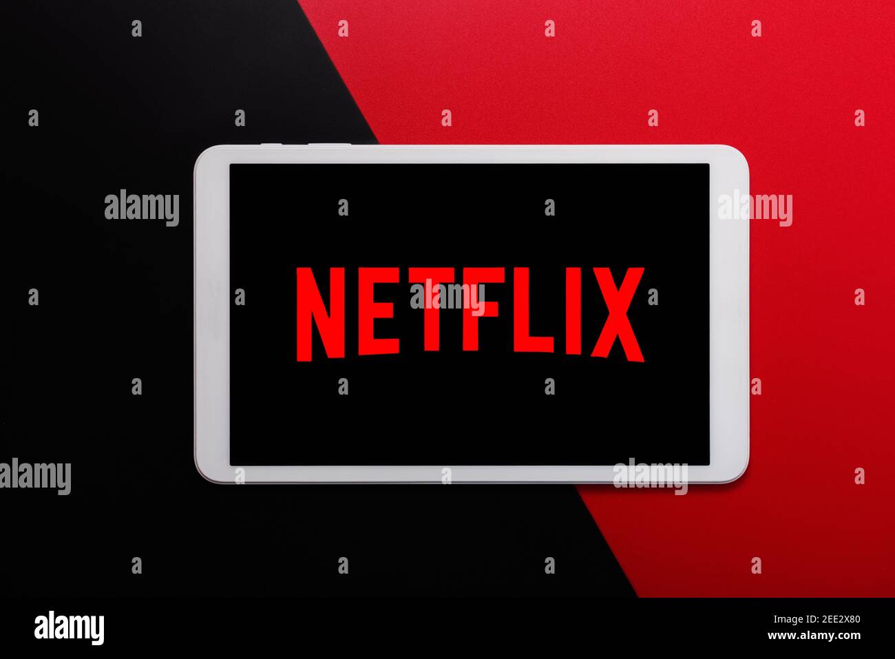 Logo Netflix sullo schermo di un tablet digitale bianco su sfondo rosso e nero Foto Stock