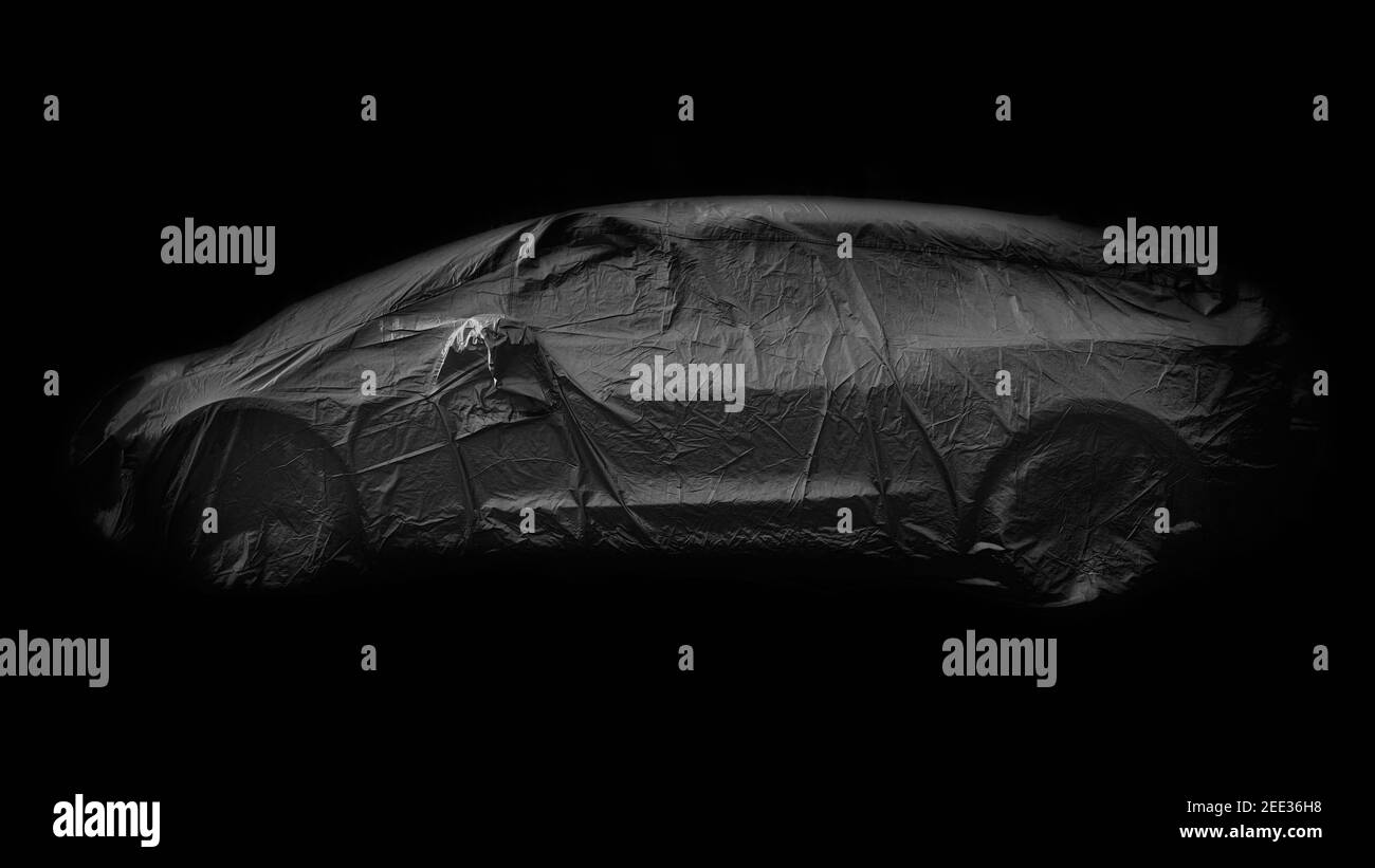 Immagine monocromatica in bianco e nero con sfondo nero sul lato vista di un'auto avvolta in un coperchio grigio protetto Foto Stock