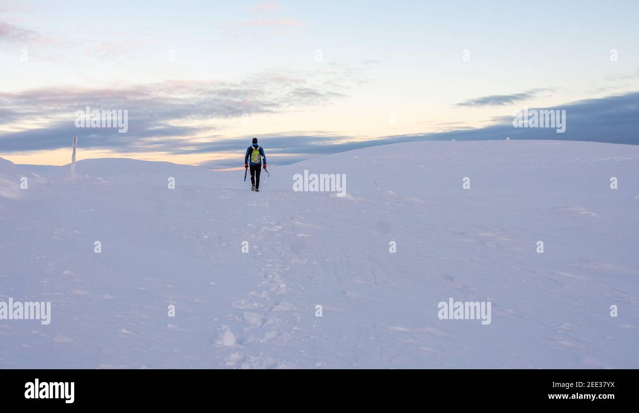 Un uomo sale sul pendio di una montagna innevata in Lapponia Foto Stock