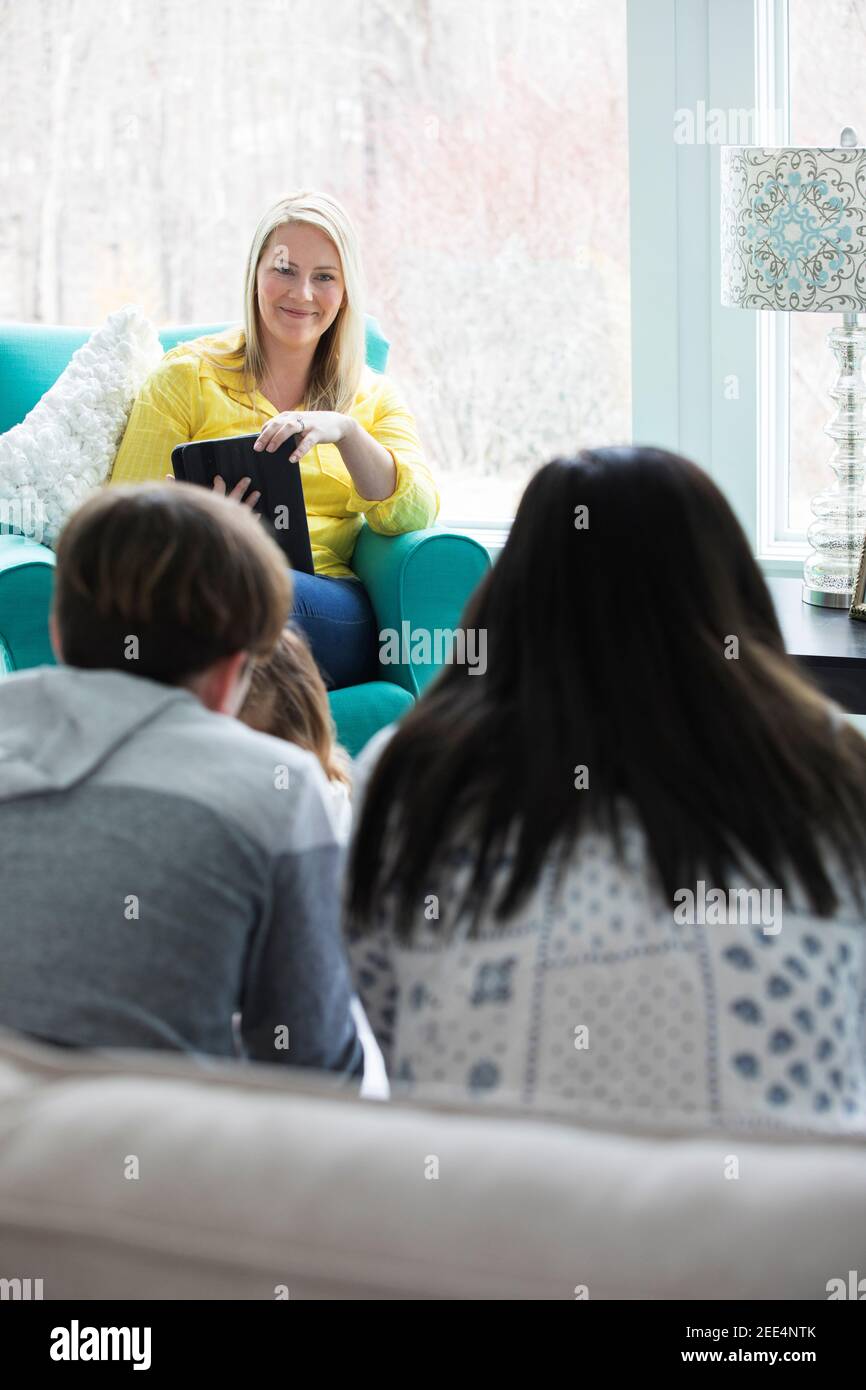 Una mamma che parla con i suoi figli in un soggiorno luminoso e moderno. Foto Stock