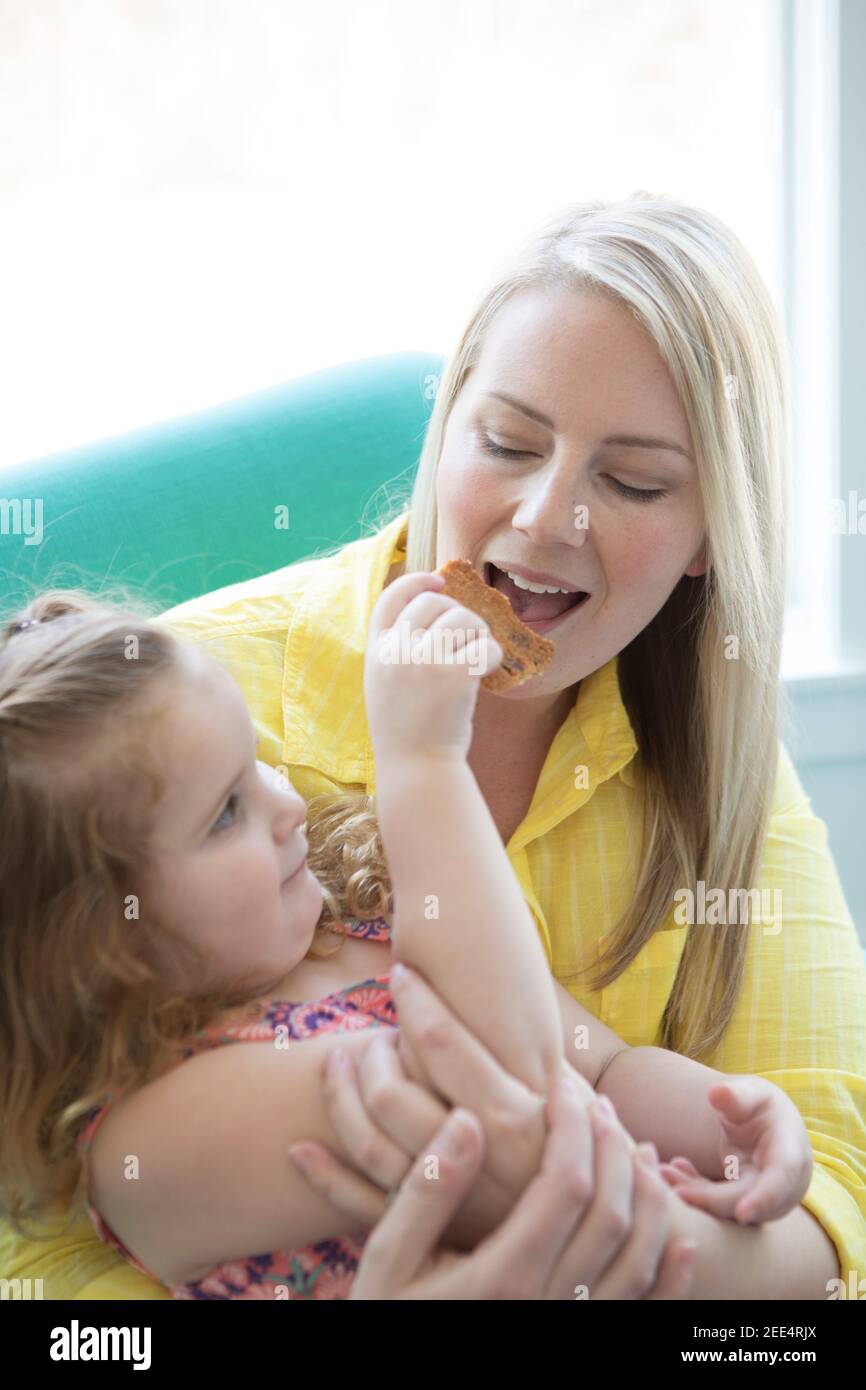 Una bambina le dà un morso biscotti al cioccolato Foto Stock