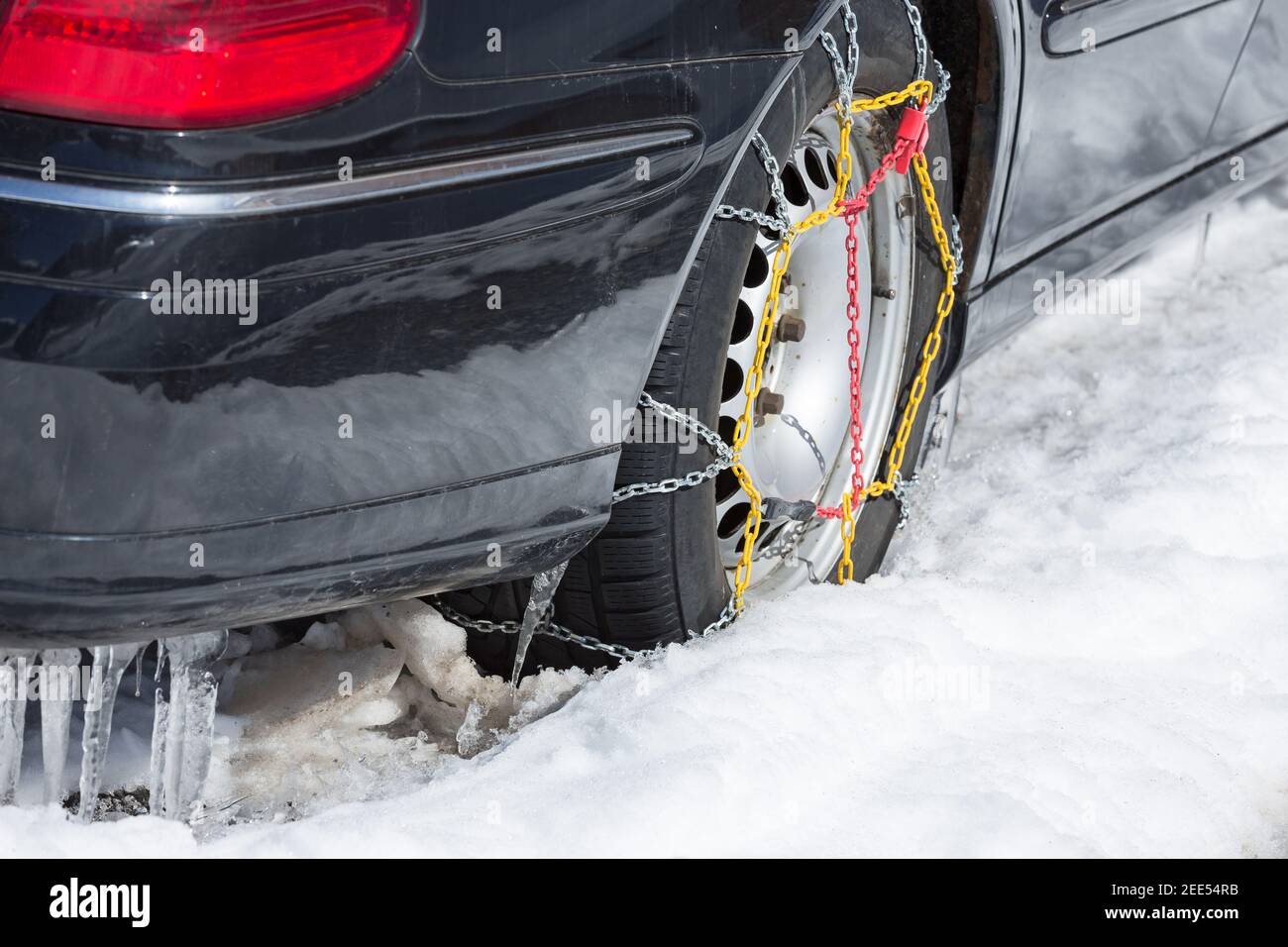 catene da neve sul pneumatico posteriore della vettura nera Foto Stock