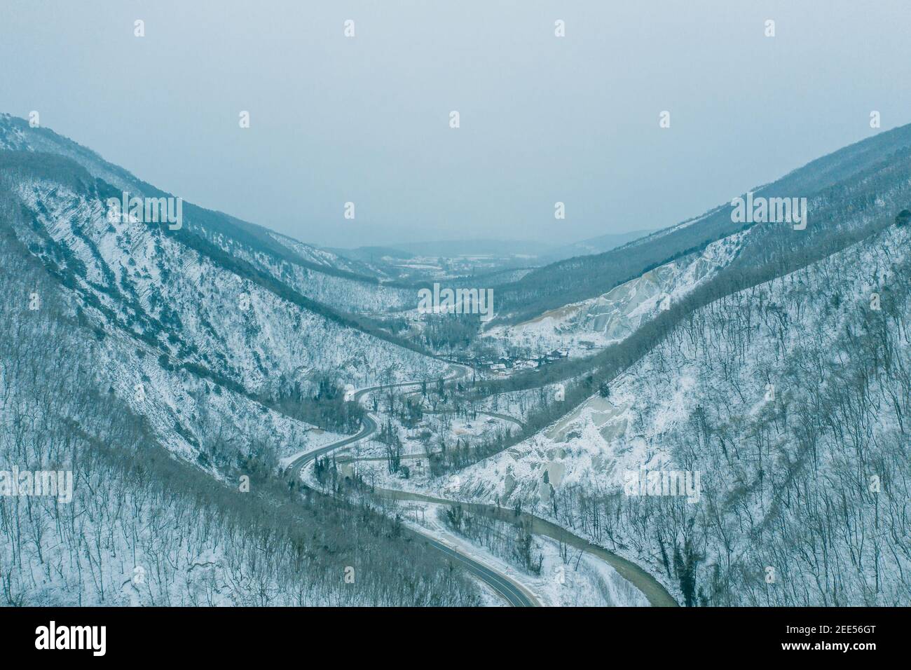 Vista aerea dal drone sopra la gola di montagna tra le vette in inverno in tempo nevoso. Foto Stock