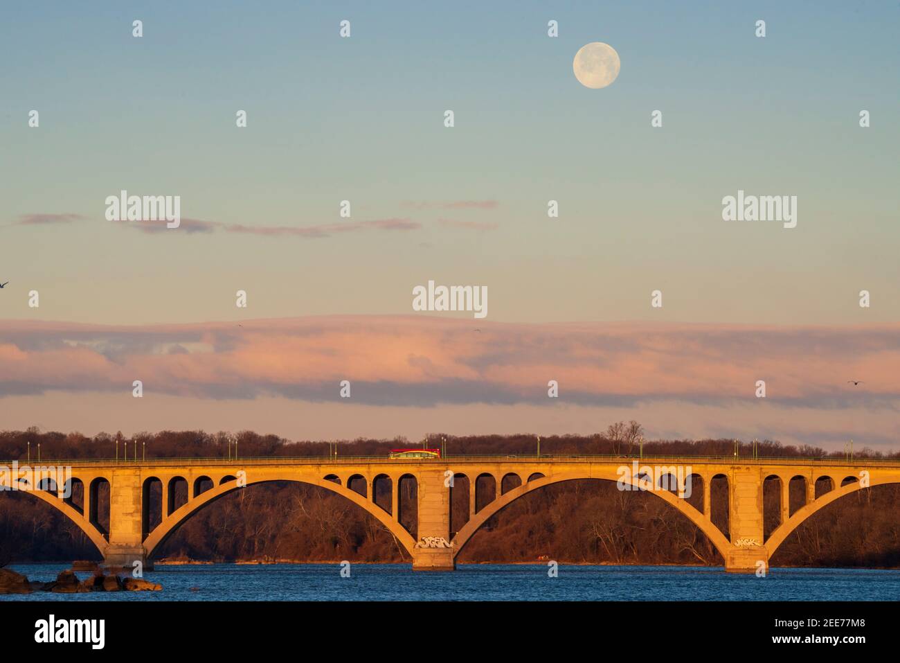 La luna piena tramonta alla luce del primo mattino su Key Bridge a Washington, DC. Foto Stock
