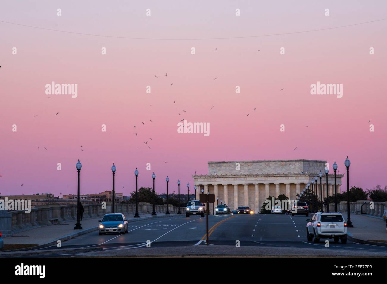 Il cielo diventa un rosa arrossito dopo che il sole scende mentre le auto attraversano il Ponte Memoriale di Arlington. Il Lincoln Memorial può essere visto nel backgro Foto Stock