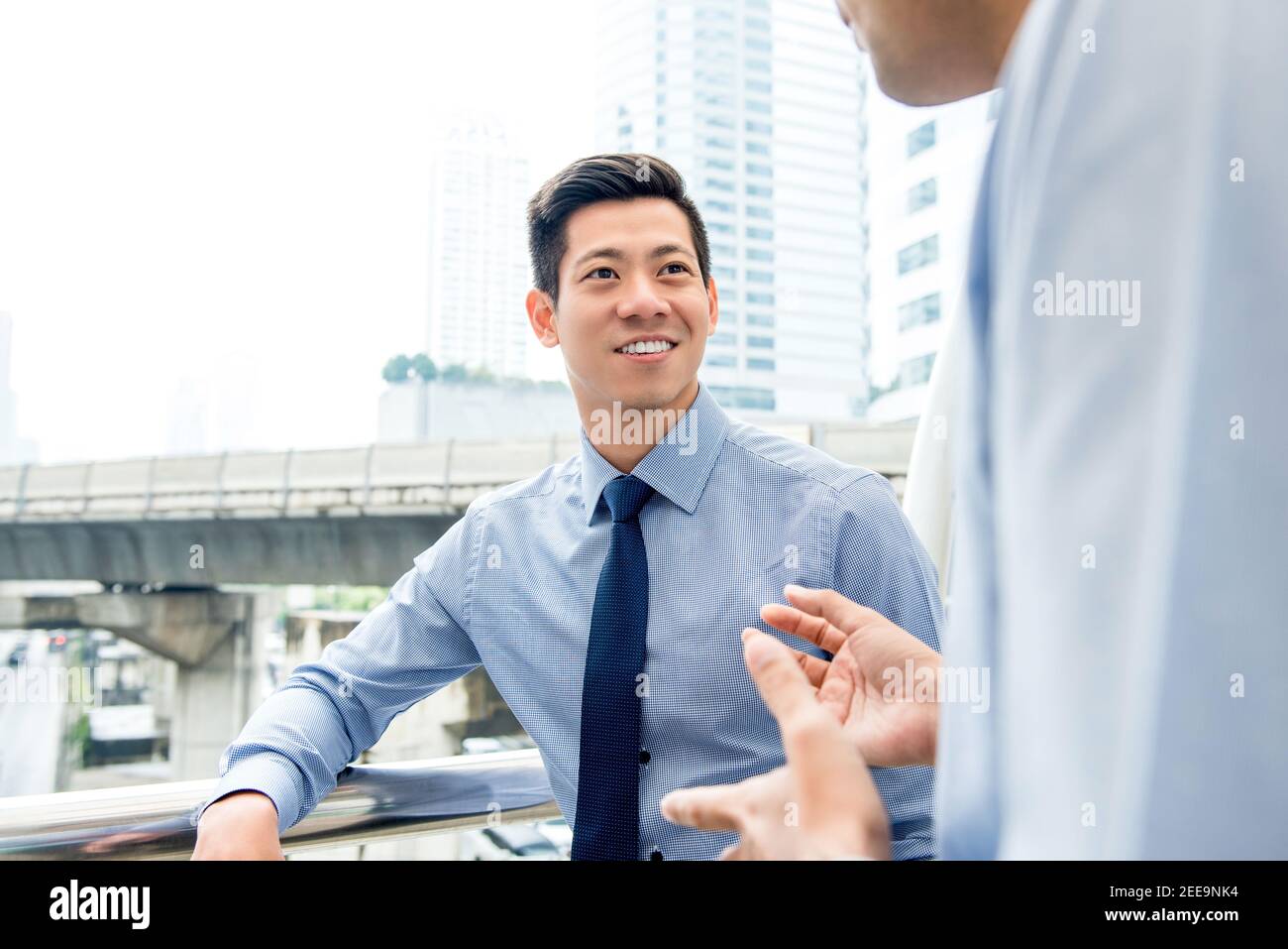 Bell'uomo d'affari cinese asiatico che parla con colleghi all'aperto nel città Foto Stock