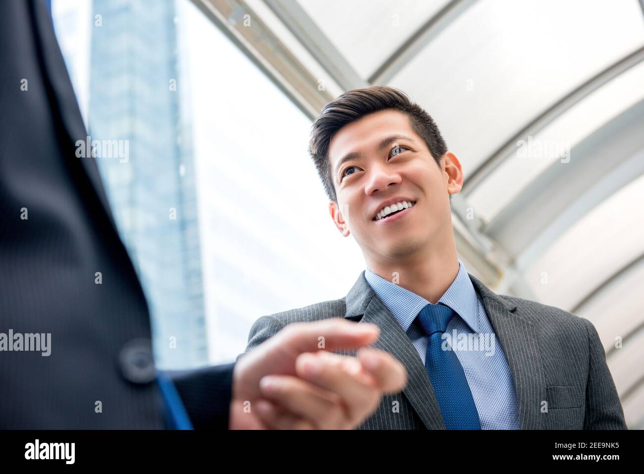 Giovane bell'uomo d'affari cinese asiatico che parla con il partner all'aperto dentro la città Foto Stock