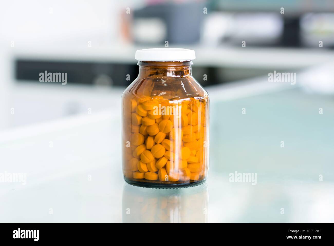 Piccole pillole in ambrato flacone di medicina al tavolo in farmacia Foto Stock