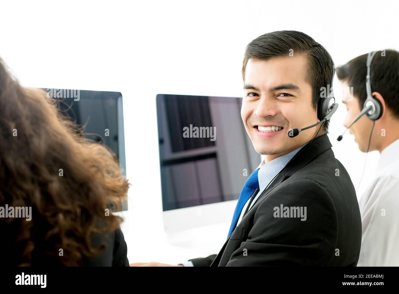 Sorridente uomo ispanico telemarketing agente servizio clienti che lavora in chiamata centrare con il suo team Foto Stock