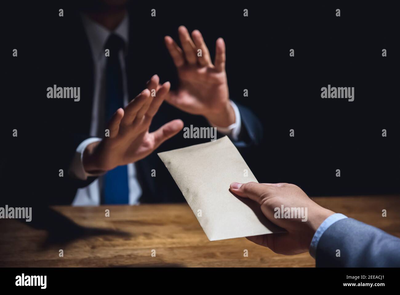 Uomo d'affari che rifiuta i soldi nella busta segretamente offerta dal suo partner al buio - concetto anticorruzione Foto Stock